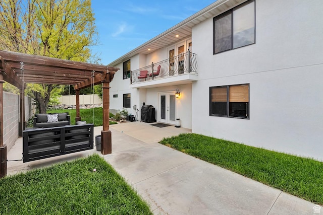 back of property with french doors, a balcony, a pergola, stucco siding, and a patio
