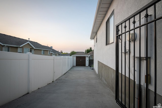 property exterior at dusk featuring fence, stucco siding, and an outdoor structure