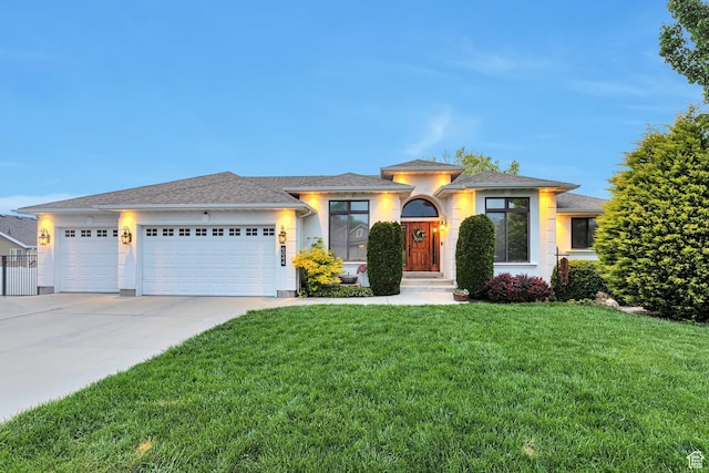 prairie-style home with a garage, concrete driveway, a front lawn, and stucco siding