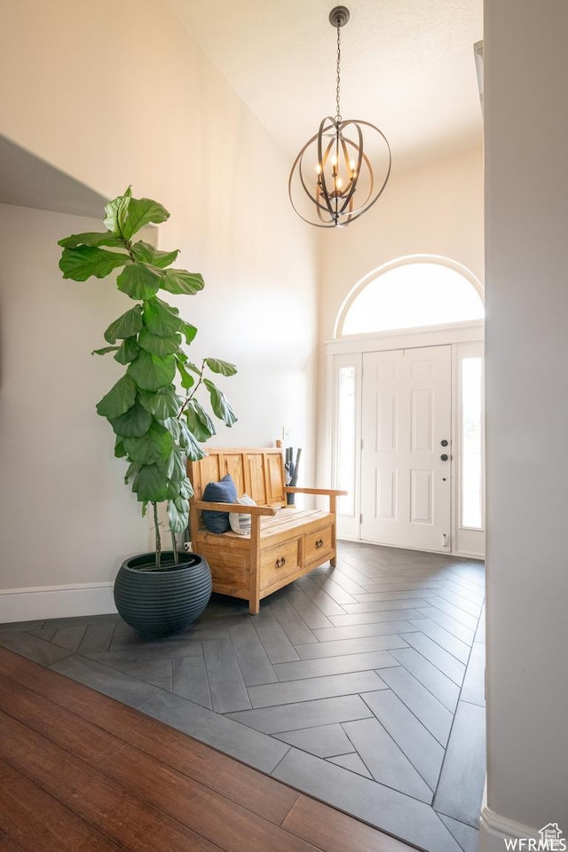 entrance foyer featuring a chandelier, wood finished floors, baseboards, and high vaulted ceiling
