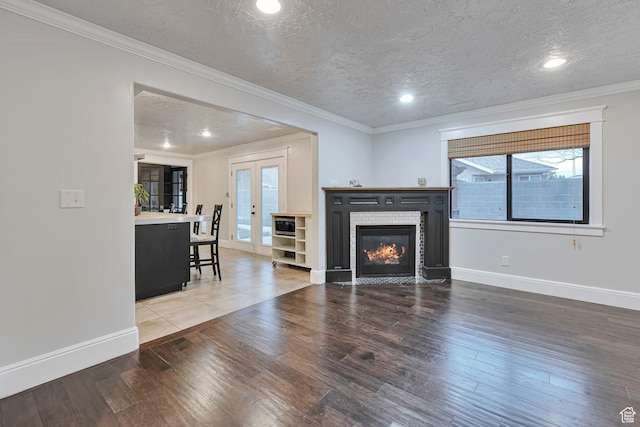 living area with plenty of natural light, baseboards, wood finished floors, a tiled fireplace, and a textured ceiling