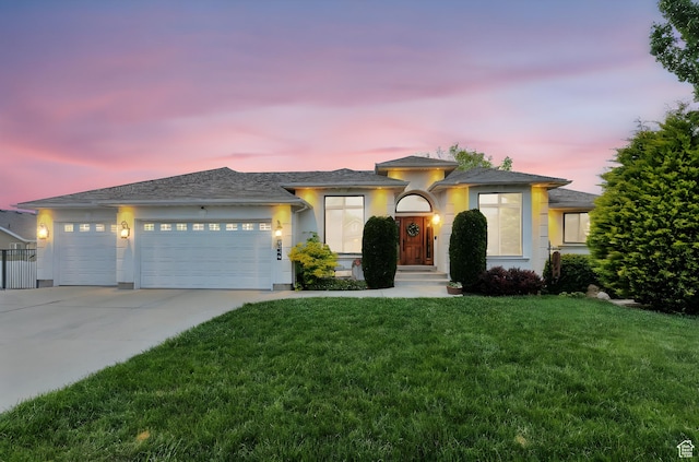 view of front of home featuring an attached garage, driveway, a yard, and stucco siding