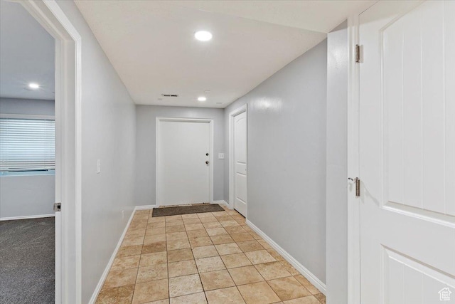hallway featuring baseboards, light stone finish floors, and recessed lighting