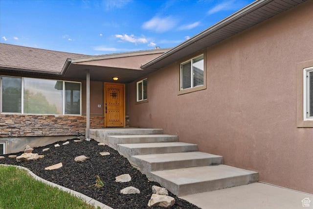 property entrance featuring stone siding and stucco siding