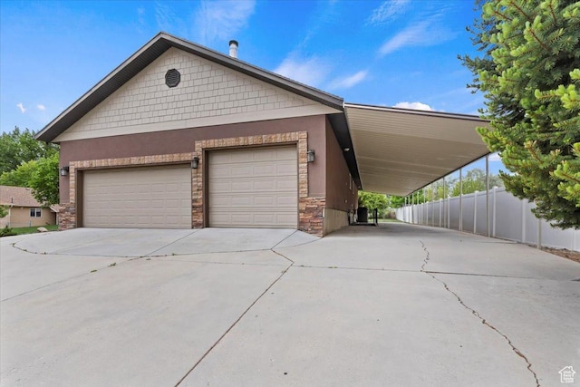 view of front of property with concrete driveway, stone siding, stucco siding, and fence