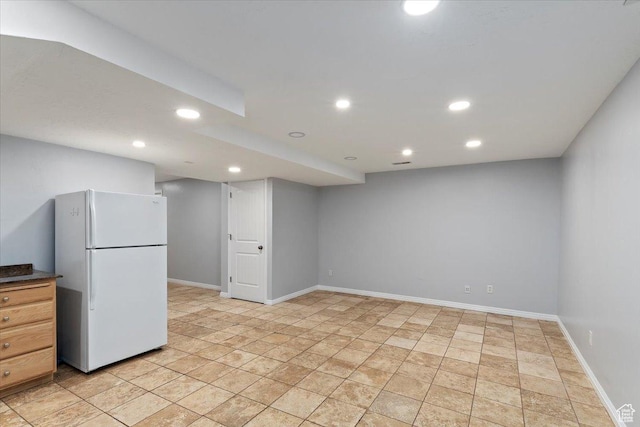 finished below grade area with freestanding refrigerator, recessed lighting, baseboards, and light stone finish floors