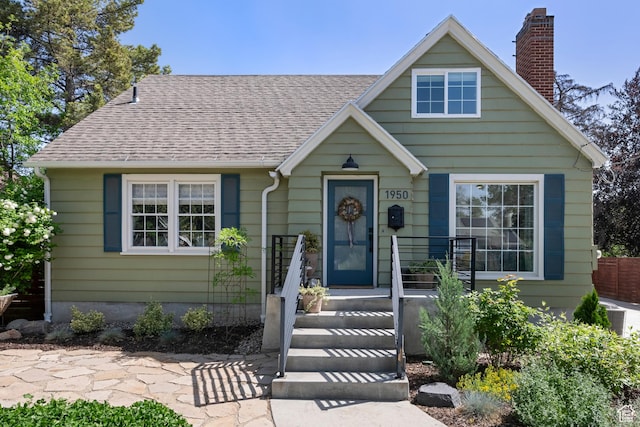 bungalow-style home featuring a chimney and a shingled roof