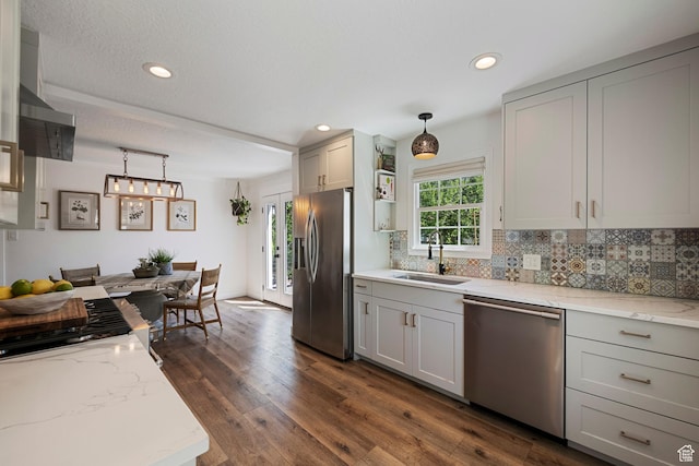 kitchen featuring appliances with stainless steel finishes, a sink, gray cabinetry, tasteful backsplash, and dark wood-style floors