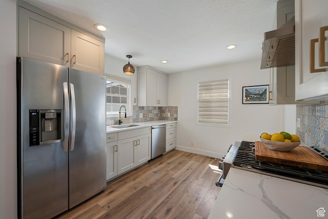 kitchen with appliances with stainless steel finishes, a sink, tasteful backsplash, plenty of natural light, and recessed lighting