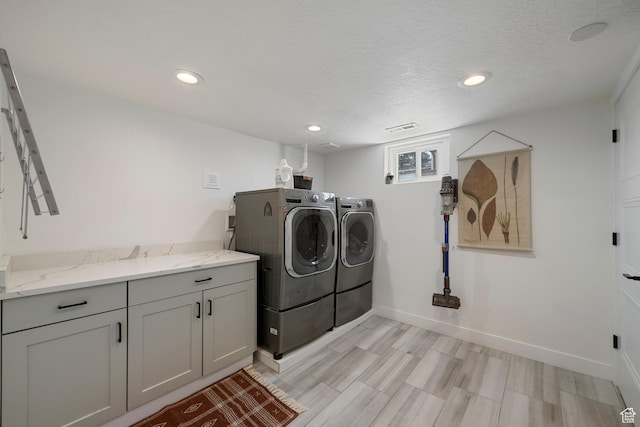 clothes washing area with washer and clothes dryer, cabinet space, baseboards, recessed lighting, and a textured ceiling