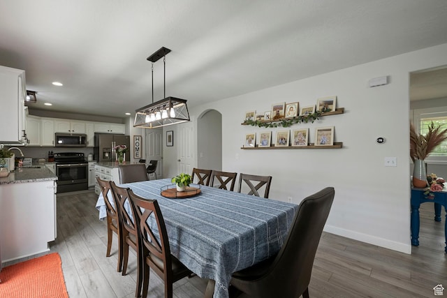dining area with arched walkways, wood finished floors, recessed lighting, and baseboards