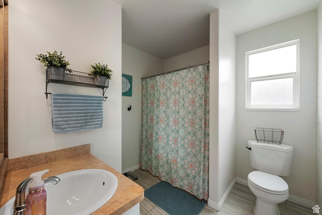 full bathroom with a sink, toilet, a shower with curtain, and baseboards