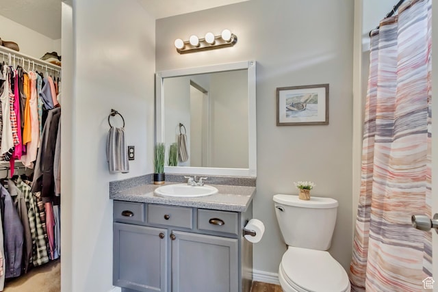 full bath with vanity, toilet, and a walk in closet