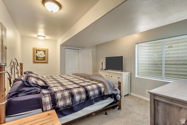 bedroom with light colored carpet, baseboards, and a closet