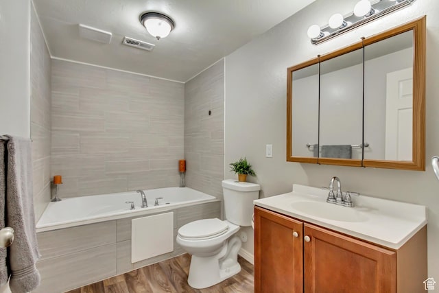 bathroom featuring wood finished floors, toilet, a bath, and vanity