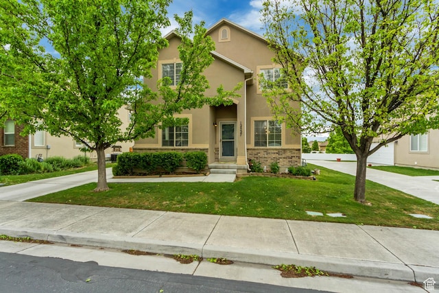 view of front of home with stucco siding, a front lawn, and brick siding