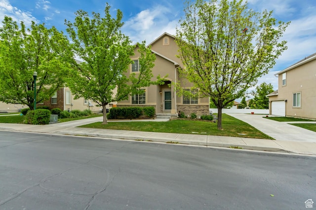 obstructed view of property featuring stucco siding, a front yard, a garage, concrete driveway, and brick siding