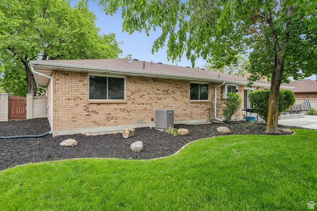 view of front of home with central AC, brick siding, a patio, and a shingled roof