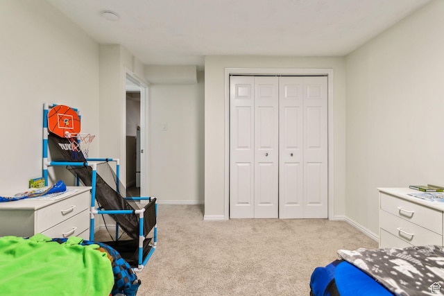 bedroom with light carpet, baseboards, and a closet