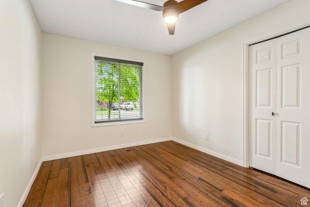 unfurnished bedroom featuring dark wood finished floors, baseboards, and a ceiling fan