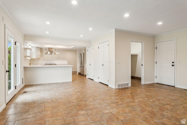 unfurnished living room featuring plenty of natural light, stone tile flooring, recessed lighting, ornamental molding, and a sink