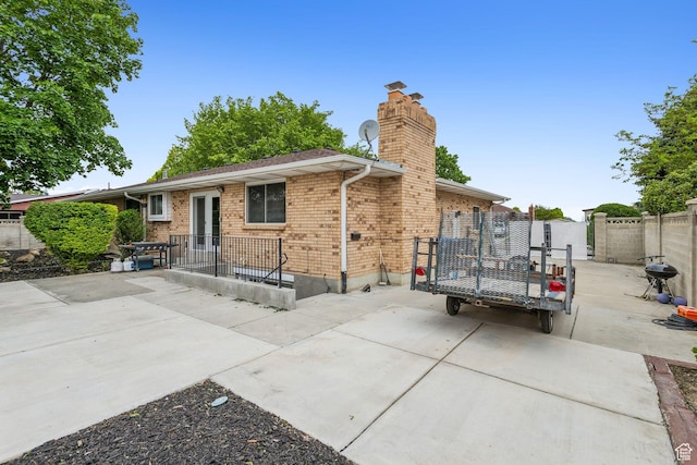 back of property featuring a patio, a chimney, fence, and brick siding