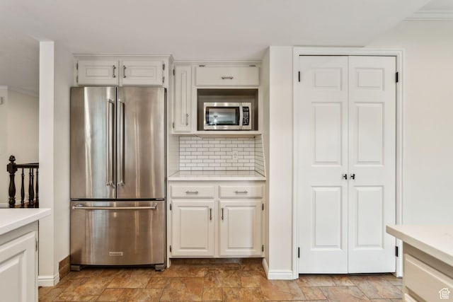 kitchen with appliances with stainless steel finishes, stone finish flooring, and light countertops