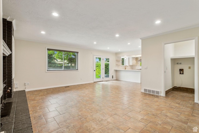 unfurnished living room featuring a fireplace, recessed lighting, stone tile floors, baseboards, and ornamental molding