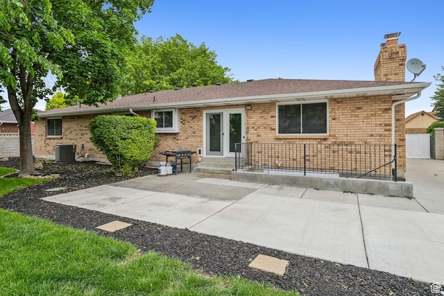 rear view of property with central air condition unit, a chimney, brick siding, and a patio area