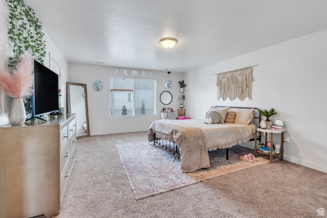 bedroom with light carpet, baseboards, and a textured ceiling