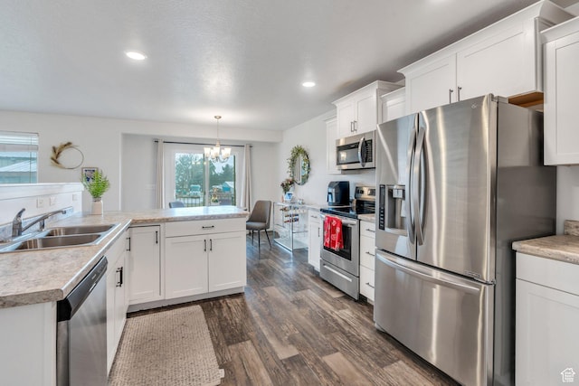 kitchen featuring stainless steel appliances, a sink, dark wood finished floors, white cabinets, and a chandelier