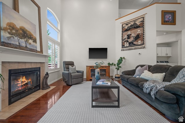 3678 S Vineyard Ct, Millcreek, UT 84106 - living room featuring a tiled fireplace, a towering ceiling, wood finished floors, and baseboards