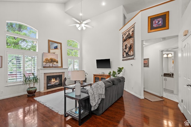 3678 S Vineyard Ct, Millcreek, UT 84106 - living area with a towering ceiling, a tiled fireplace, a ceiling fan, wood finished floors, and baseboards