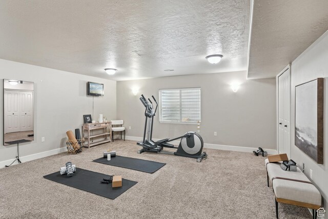 exercise area with a textured ceiling, baseboards, and carpet flooring