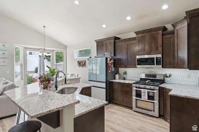 kitchen featuring stainless steel appliances, a sink, backsplash, lofted ceiling, and dark brown cabinets