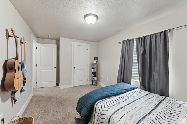 bedroom featuring light colored carpet, a textured ceiling, and baseboards
