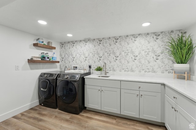 clothes washing area with washer and dryer, recessed lighting, light wood-type flooring, baseboards, and cabinet space