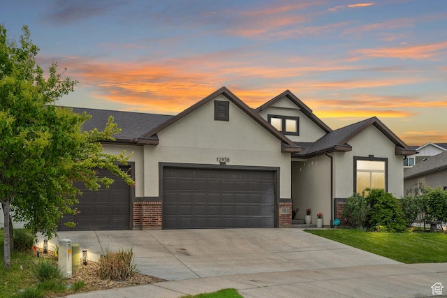 traditional-style home featuring stucco siding, an attached garage, driveway, and brick siding