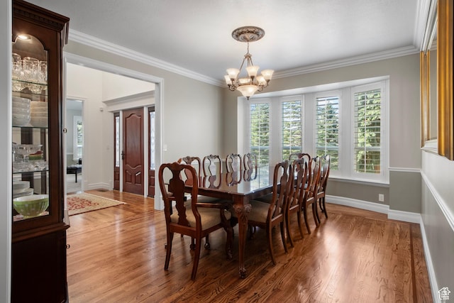 dining space with a chandelier, wood finished floors, crown molding, and baseboards