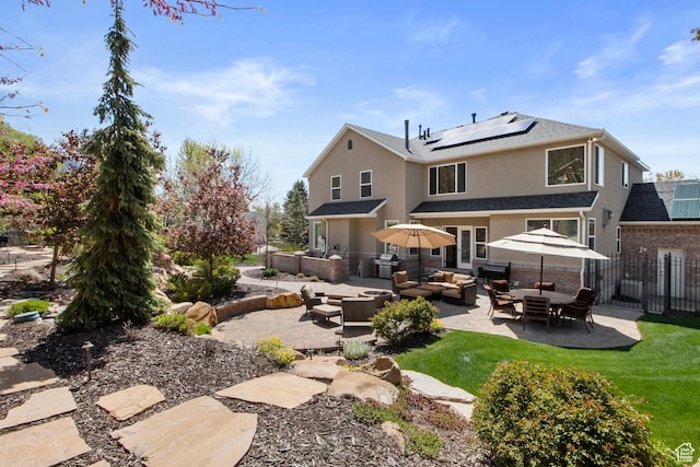 back of property featuring outdoor lounge area, stucco siding, a patio area, solar panels, and fence