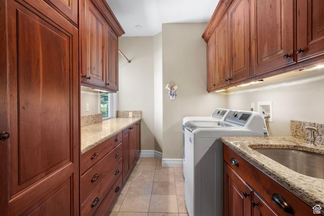 washroom featuring washer and dryer, baseboards, cabinet space, and light tile patterned flooring