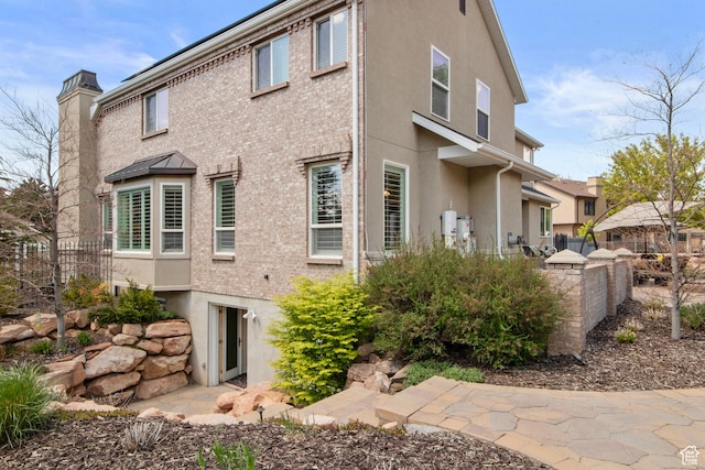 rear view of property featuring fence, stucco siding, and a chimney