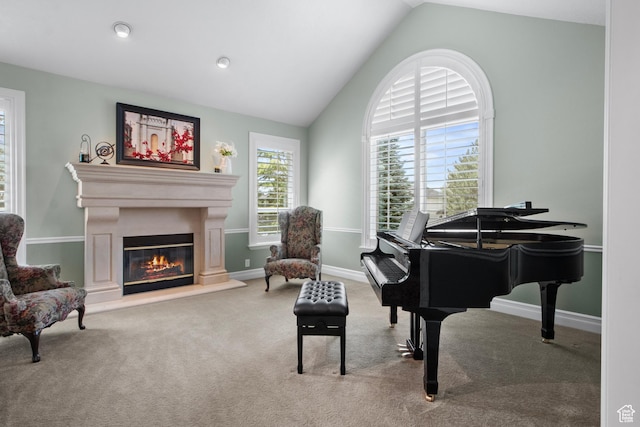 living area featuring lofted ceiling, a glass covered fireplace, carpet flooring, and baseboards