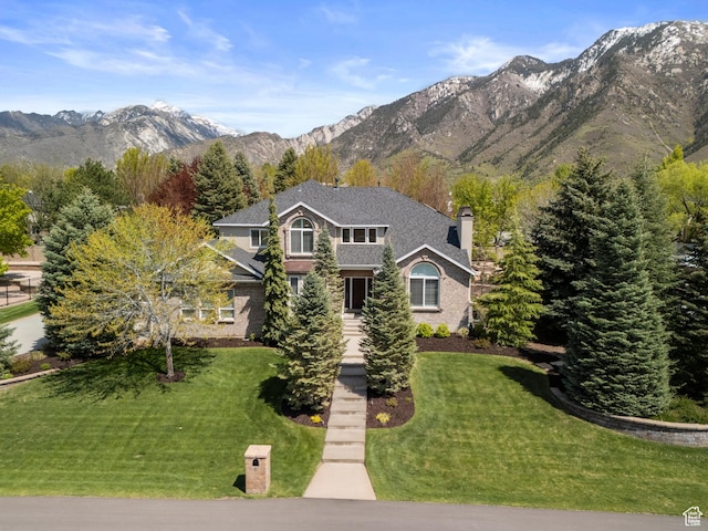 view of front of home with a mountain view, a front yard, and a chimney