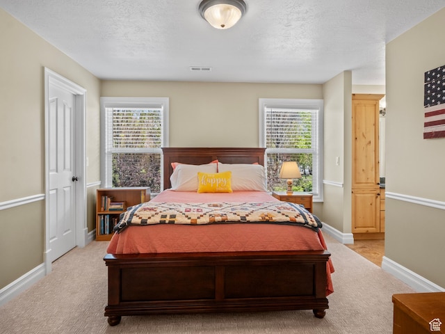 bedroom with light carpet, baseboards, and a textured ceiling