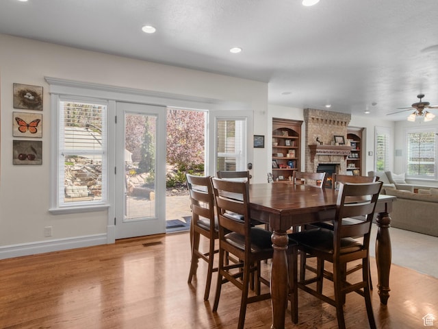 dining area featuring a fireplace, wood finished floors, ceiling fan, recessed lighting, and baseboards