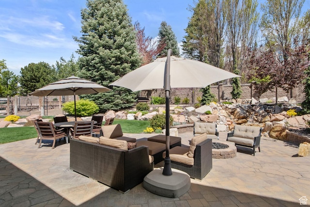 view of patio with an outdoor living space with a fire pit and fence
