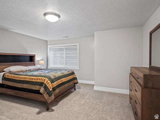 bedroom featuring light carpet, a textured ceiling, and baseboards