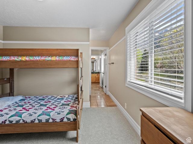 bedroom featuring light tile patterned flooring, light carpet, and baseboards
