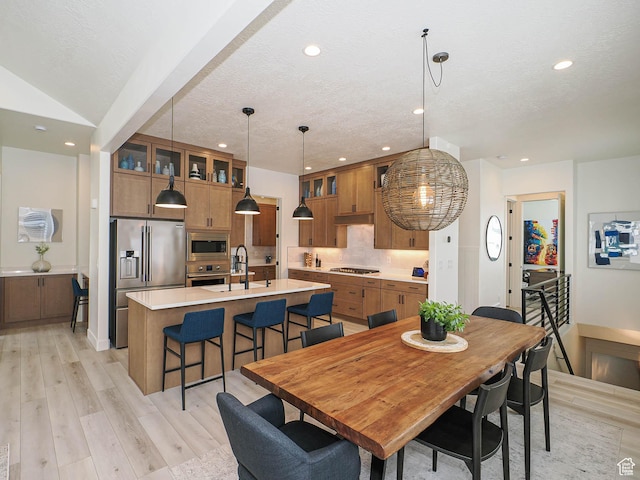 dining space with recessed lighting, light wood finished floors, a textured ceiling, and baseboards